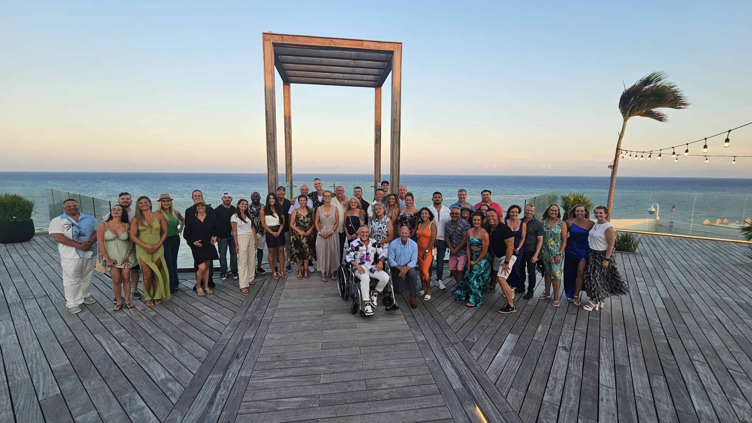 Group retreat on oceanfront deck at sunset with diverse participants and scenic views.