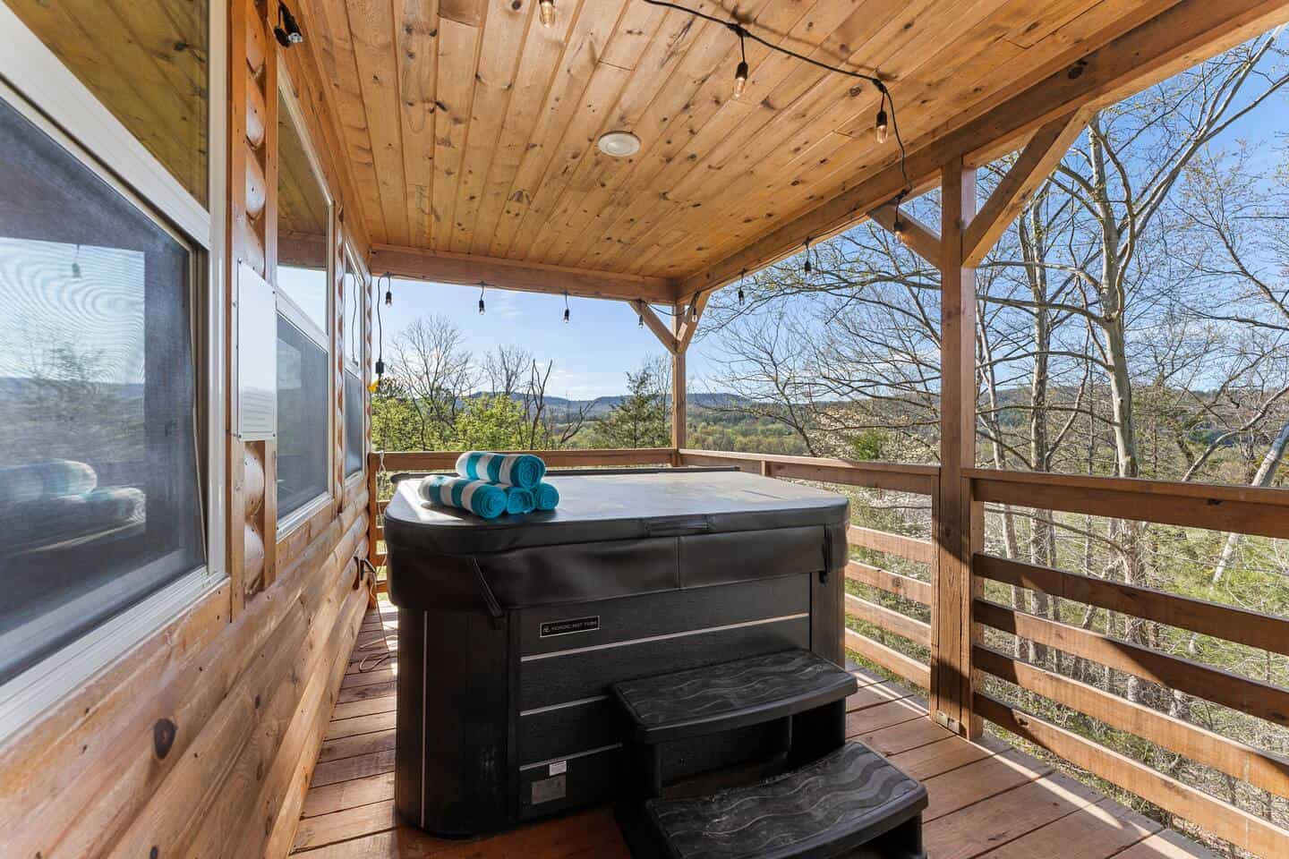 Hot tub on a cozy wooden deck with scenic forest views and clear blue sky. Perfect for relaxation an.
