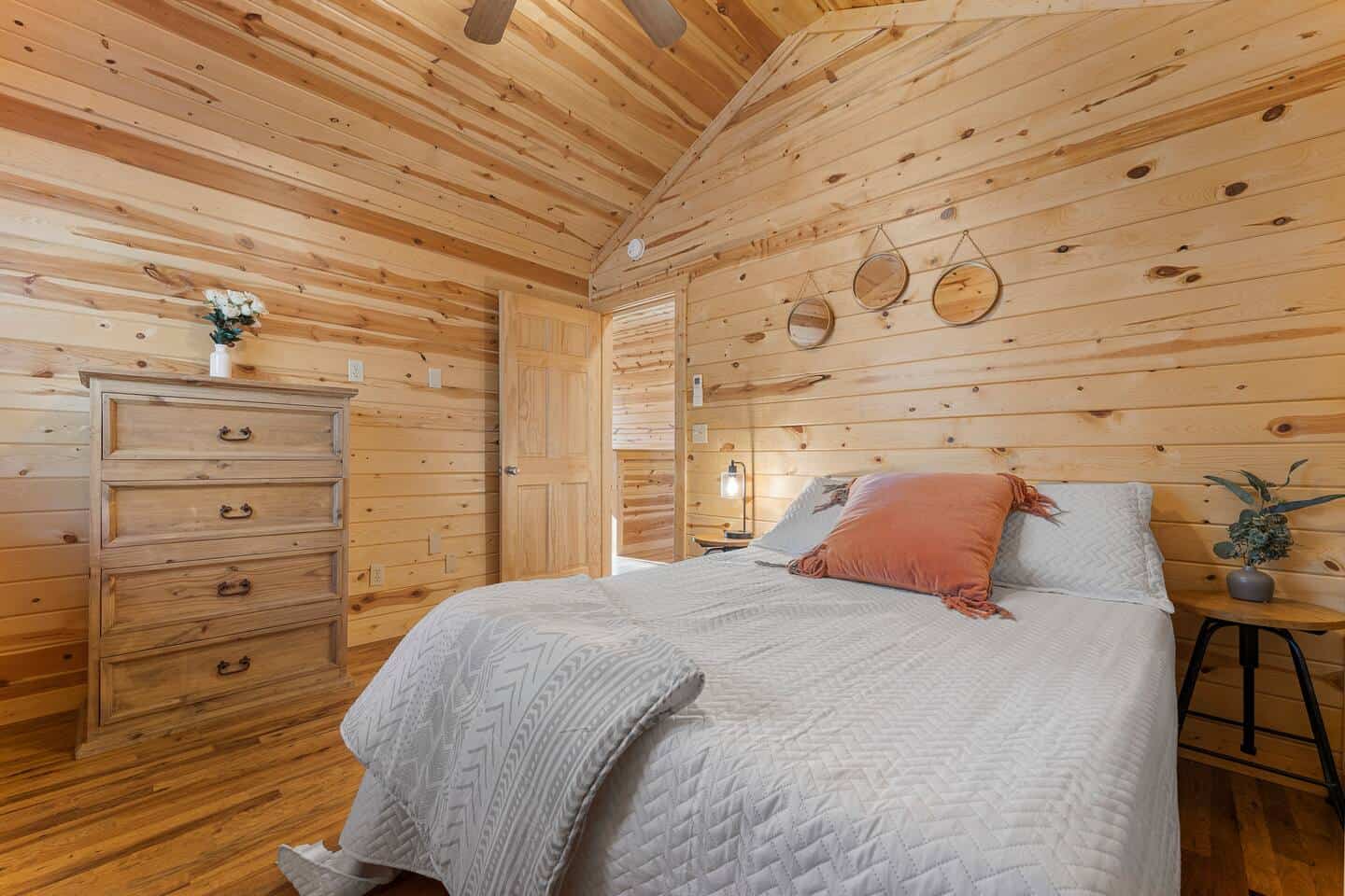 Warm wooden bedroom with cozy bed, soft pillows, and rustic decor.