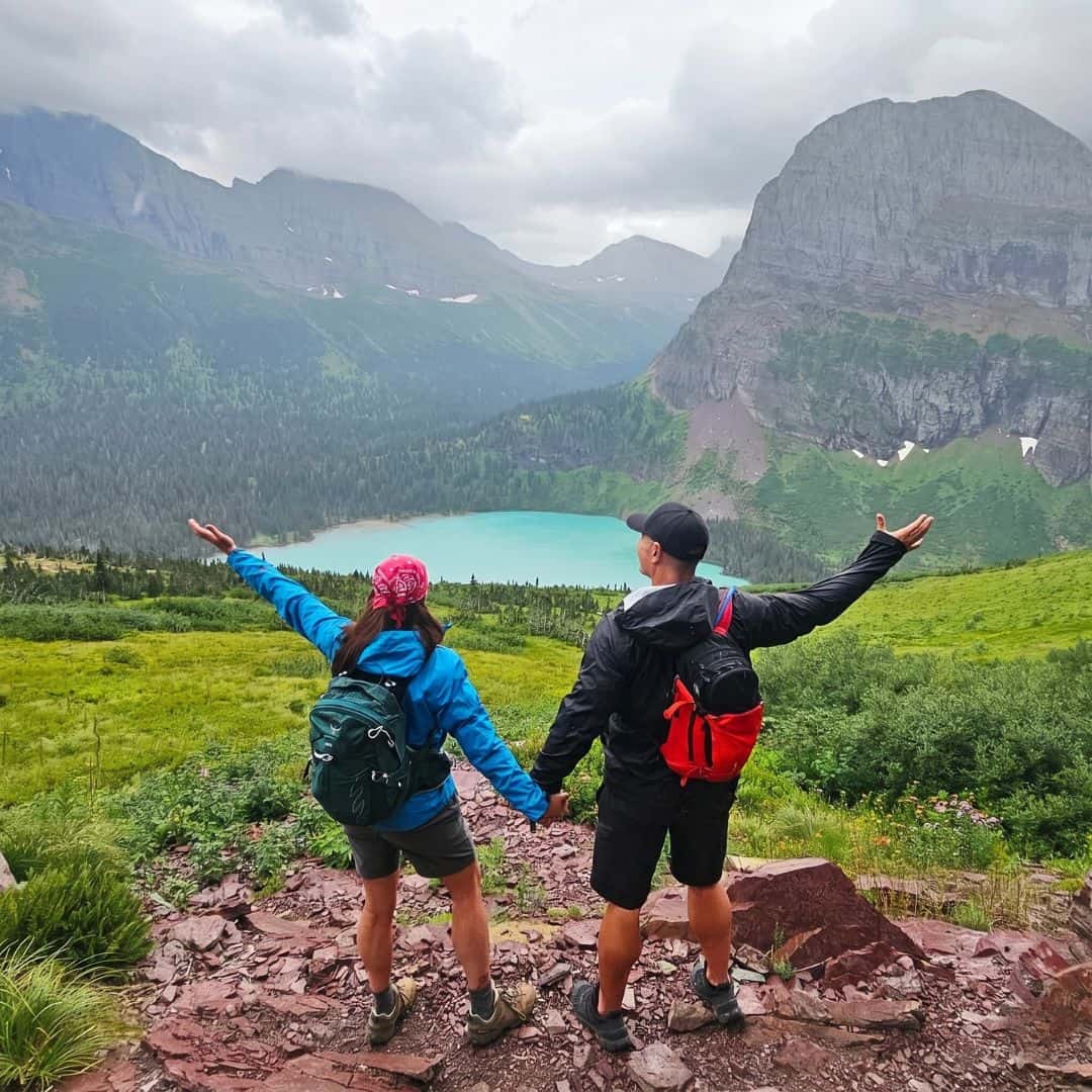 Hiking couple with backpacks enjoying scenic mountain lake view.
